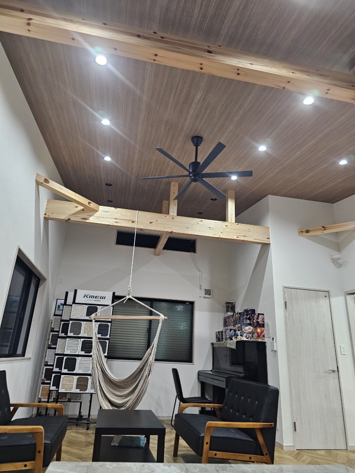 高い吹き抜けとヘリンボーンの床が特徴的なサンホームのオフィス内観。ハンモックやピアノがあり、注文住宅のアイデアが広がる商談スペースです。