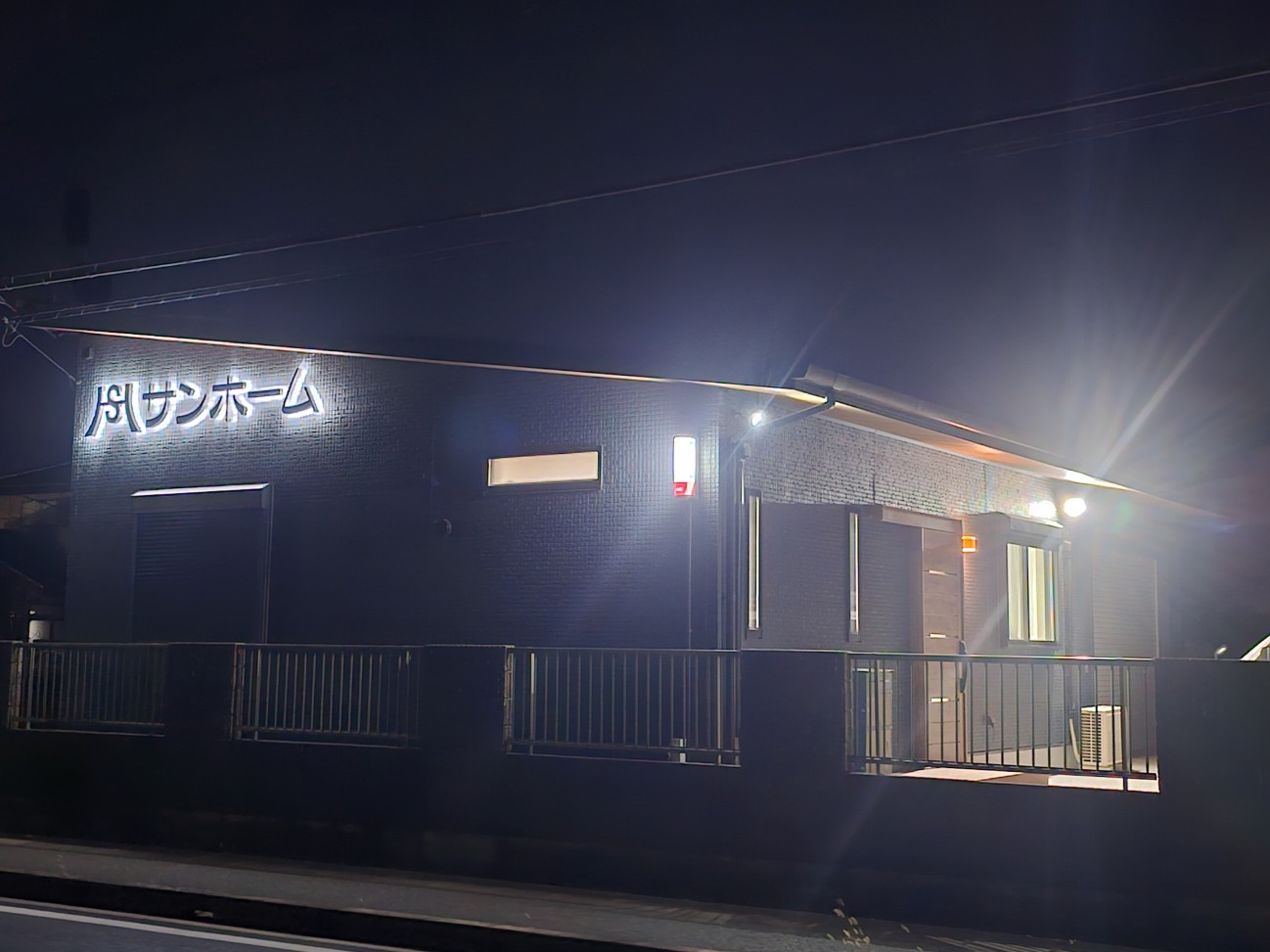 千葉県八街市の総合建設業、有限会社サンホームの新社屋外観。夜間もライトアップされたモダンな建物です。